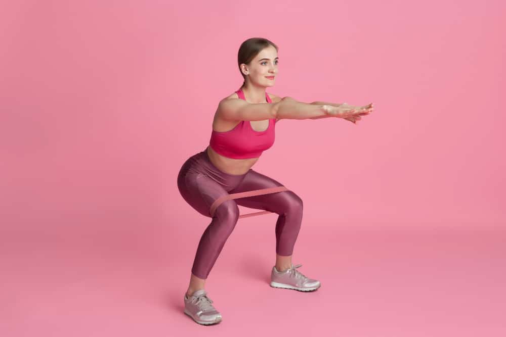 image of a woman doing squats with a resistance bands